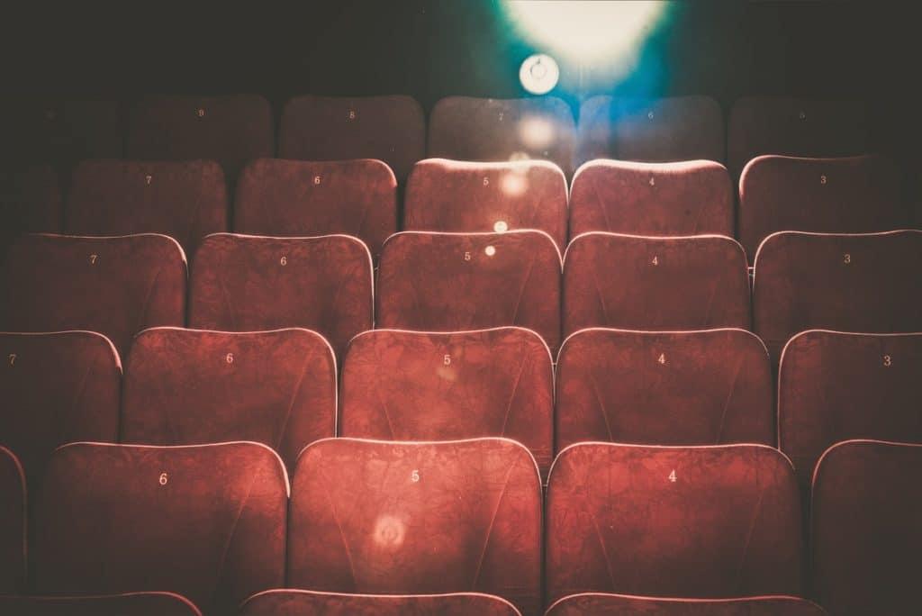 rows of red cinema seats with a light flare from the projector in the top right